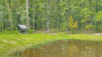 Ein Campingplatz mit Zelt und Picknicktisch in einer bewaldeten Gegend mit Teich.