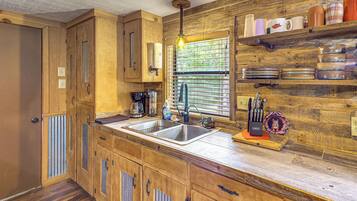 A kitchen with wooden cabinets, a double sink, and a window with blinds.