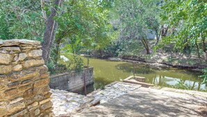A stone wall, a concrete platform, and a calm water body surrounded by greenery. - Boat Ramp Access! Canalfront Granbury Escape (Granbury)