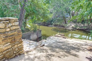 A stone wall, a concrete platform, and a calm water body surrounded by greenery. - Boat Ramp Access! Canalfront Granbury Escape (Granbury)