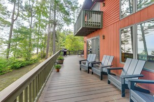 Una terraza de madera con mobiliario exterior y vistas al bosque circundante.