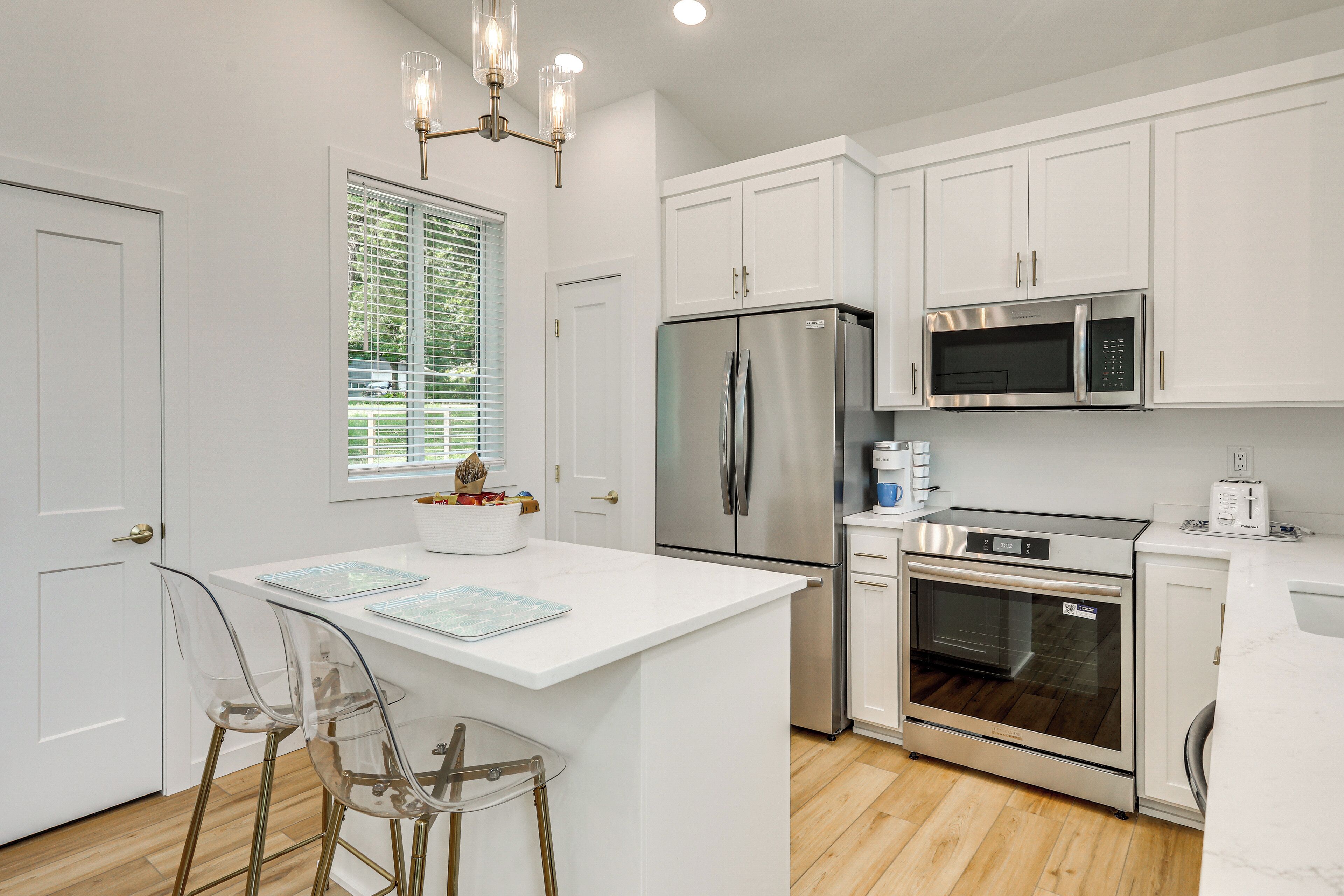 A modern kitchen with white cabinetry, stainless steel appliances, and a central island with bar stools.