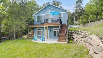 A two-story house with a balcony, a stone retaining wall, and a grassy yard.