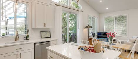 A modern kitchen with white cabinetry, a central island, and a dining area with a table and chairs.