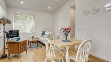 A modern living room with a dining area, a telescope, and a large window with blinds.