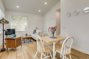 A modern living room with a dining area, a telescope, and a large window with blinds.
