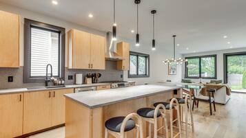A modern kitchen with wooden cabinets, a central island with bar stools, and pendant lighting.