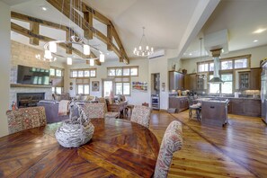 A spacious living area with a wooden dining table, patterned chairs, and a fireplace.