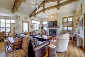 A spacious living room with a fireplace, leather sofas, and a large television.