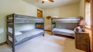 Habitación con dos literas, ventilador de techo, lámpara y una pequeña mesa con un adorno.