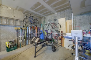 A garage with bicycles, skis, and a weight bench.