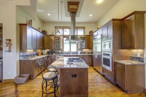 A spacious kitchen with wooden cabinets, a central island, bar stools, and modern appliances.