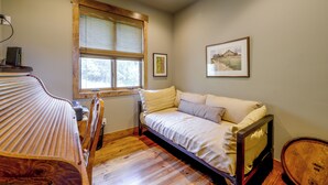 Un dormitorio con una cama de madera, una ventana con vistas y un cuadro en la pared.