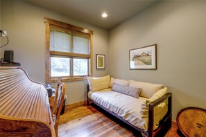 A bedroom with a wooden bed, a window with a view, and a framed picture on the wall.