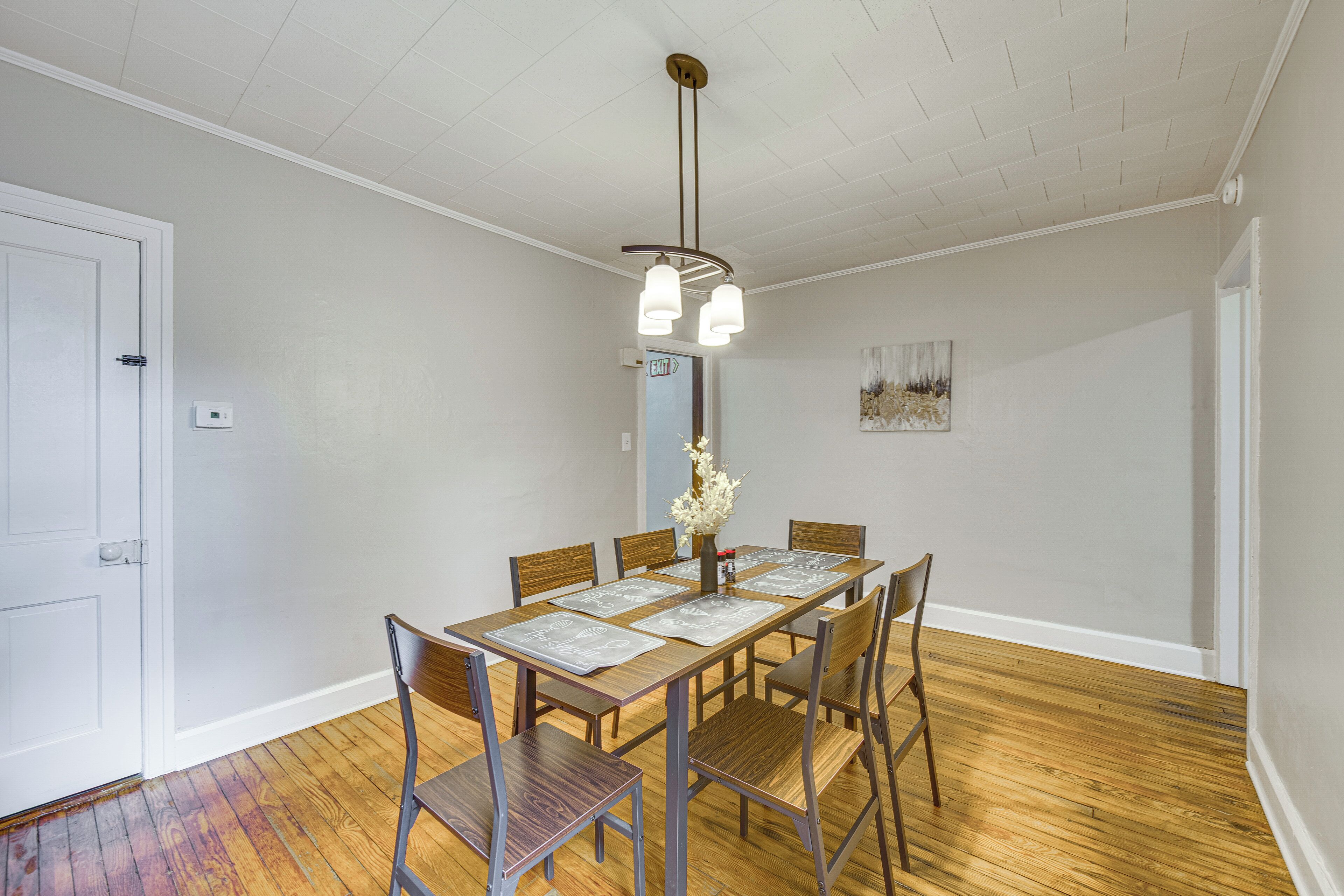 A dining area with a wooden table, chairs, and a hanging light fixture.