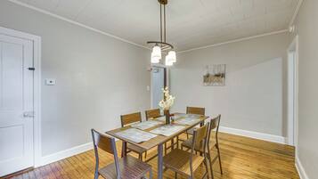 A dining area with a wooden table, chairs, and a hanging light fixture.