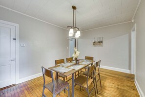 Uma sala de jantar com uma mesa de madeira, cadeiras e um lustre.