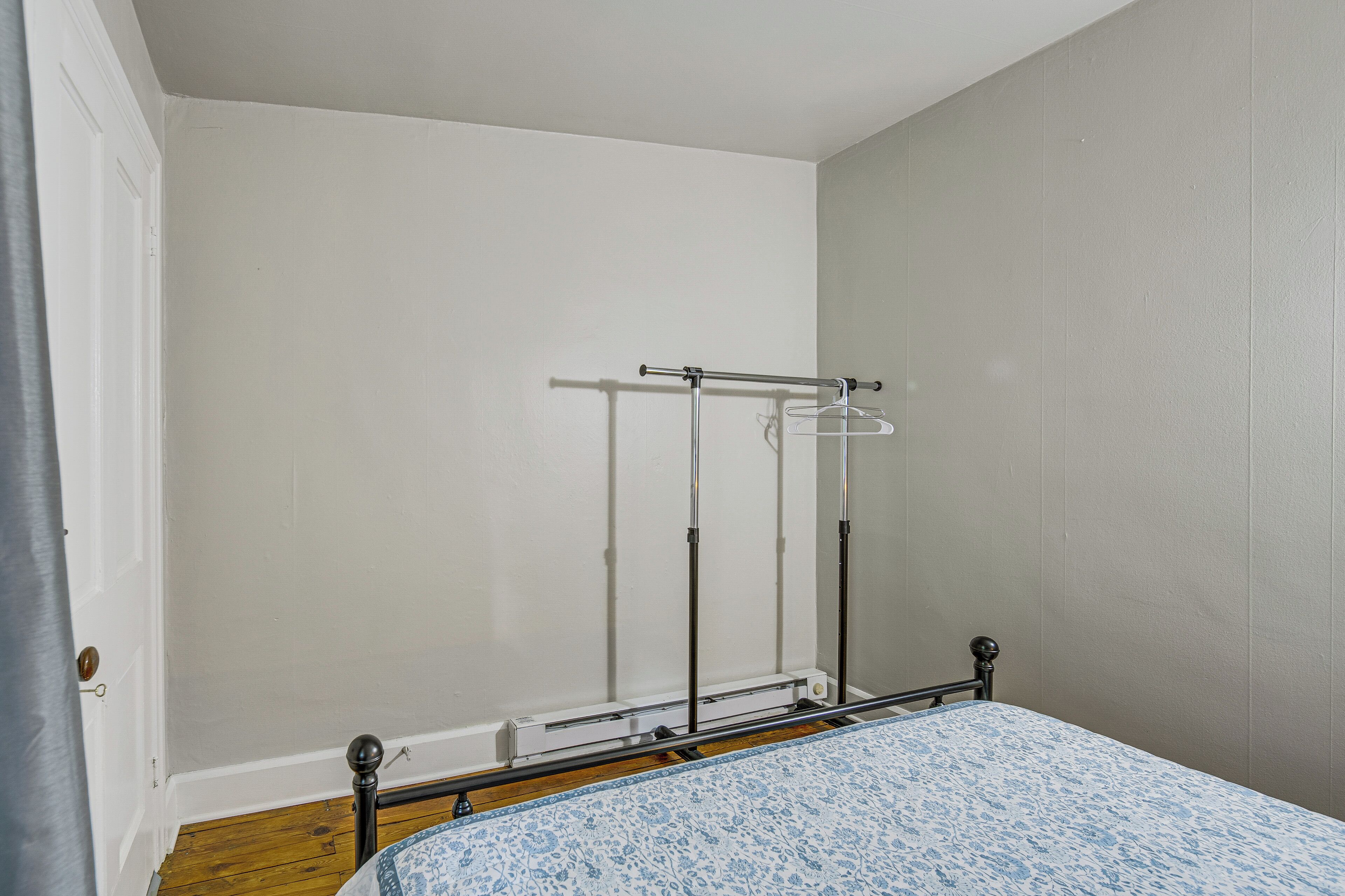 Un dormitorio con cama, armario metálico y un tendedero de pared.