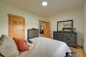 Un dormitorio con cama, dos puertas de madera, un aparador y un espejo.