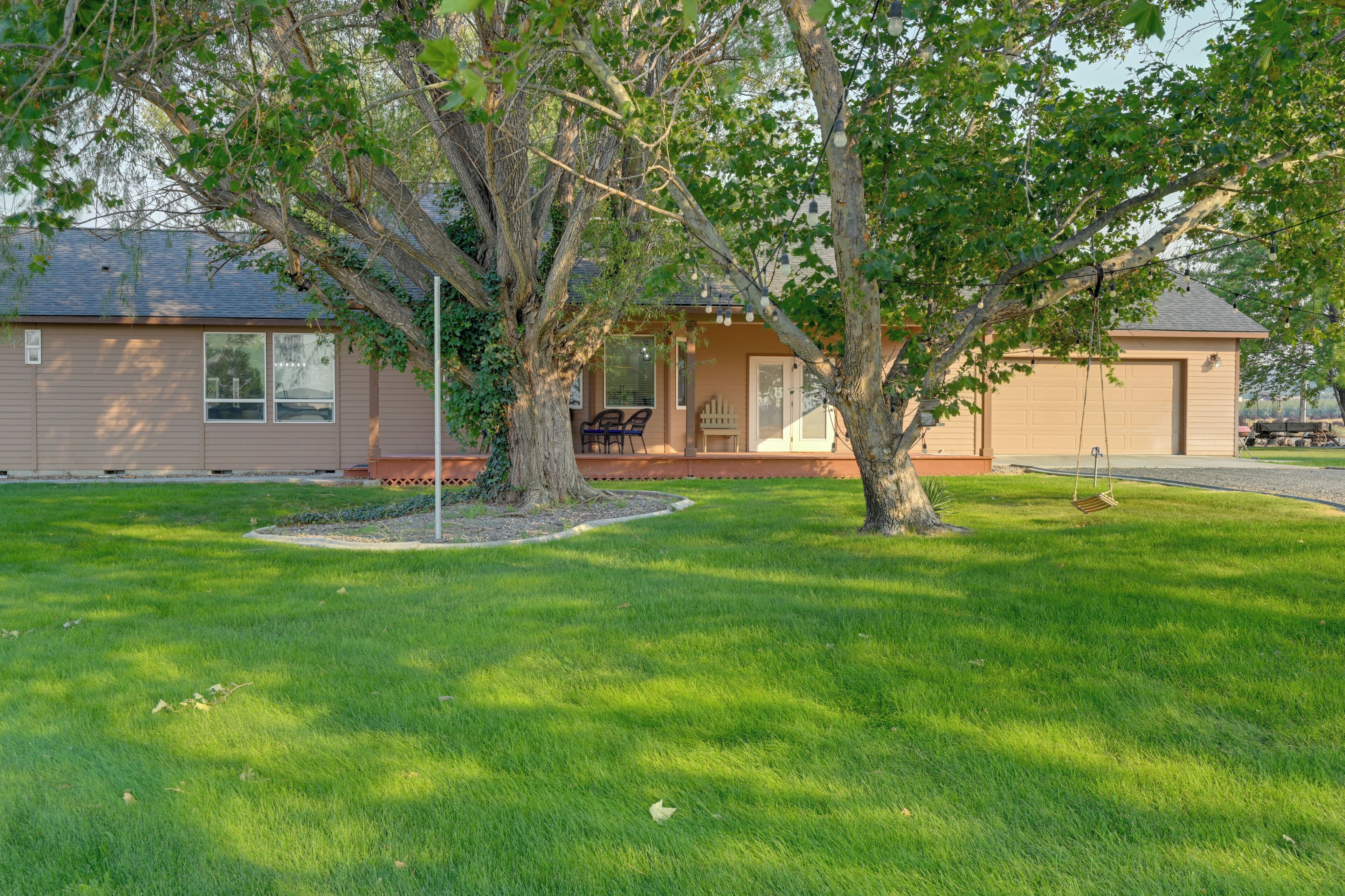 A residential property with a lawn, a tree, and a house with a garage.