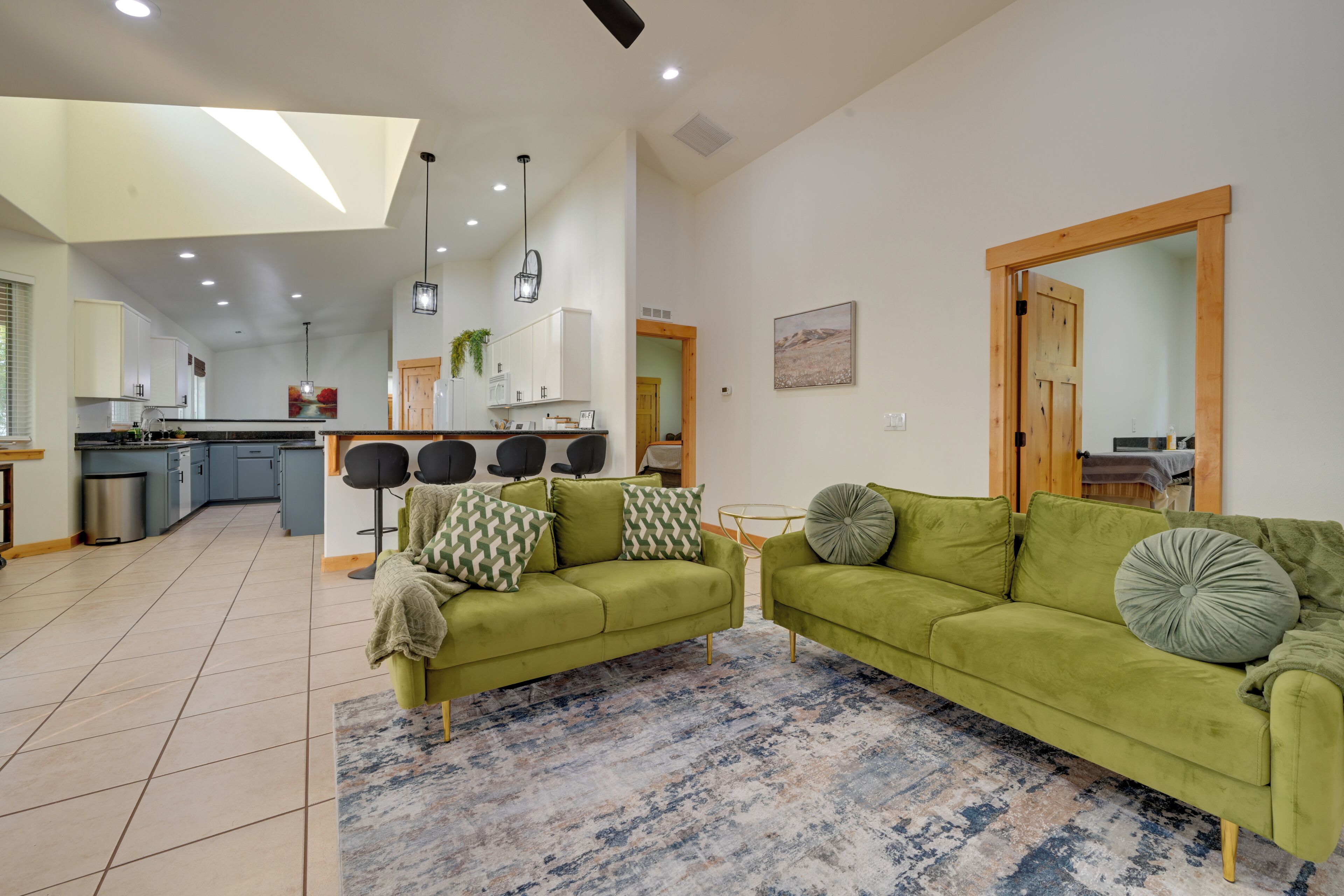 A spacious living area with a green sofa set, a coffee table, and a patterned rug.