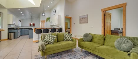Un vaste espace de vie agrémenté d’un canapé vert, d’une table basse et d’un tapis à motifs.