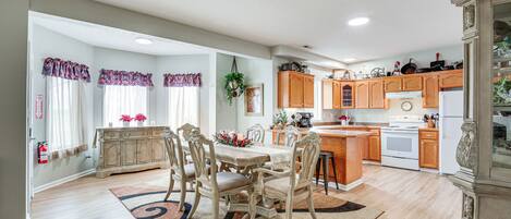 A spacious kitchen with wooden cabinets, a dining area with a table and chairs, and a large island.