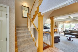A staircase with wooden railings and carpeted steps leading to a living area with a sofa, coffee table, and a television.