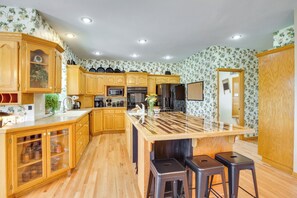 A kitchen with wooden cabinets, a central island, bar stools, and a refrigerator.