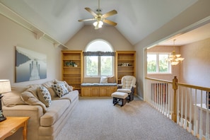 A cozy room with a high ceiling, a ceiling fan, a large window, a cushioned bench, a chair, and a staircase with a railing. - Studio Suite & Country Views! Sibley Group Retreat (Sibley)