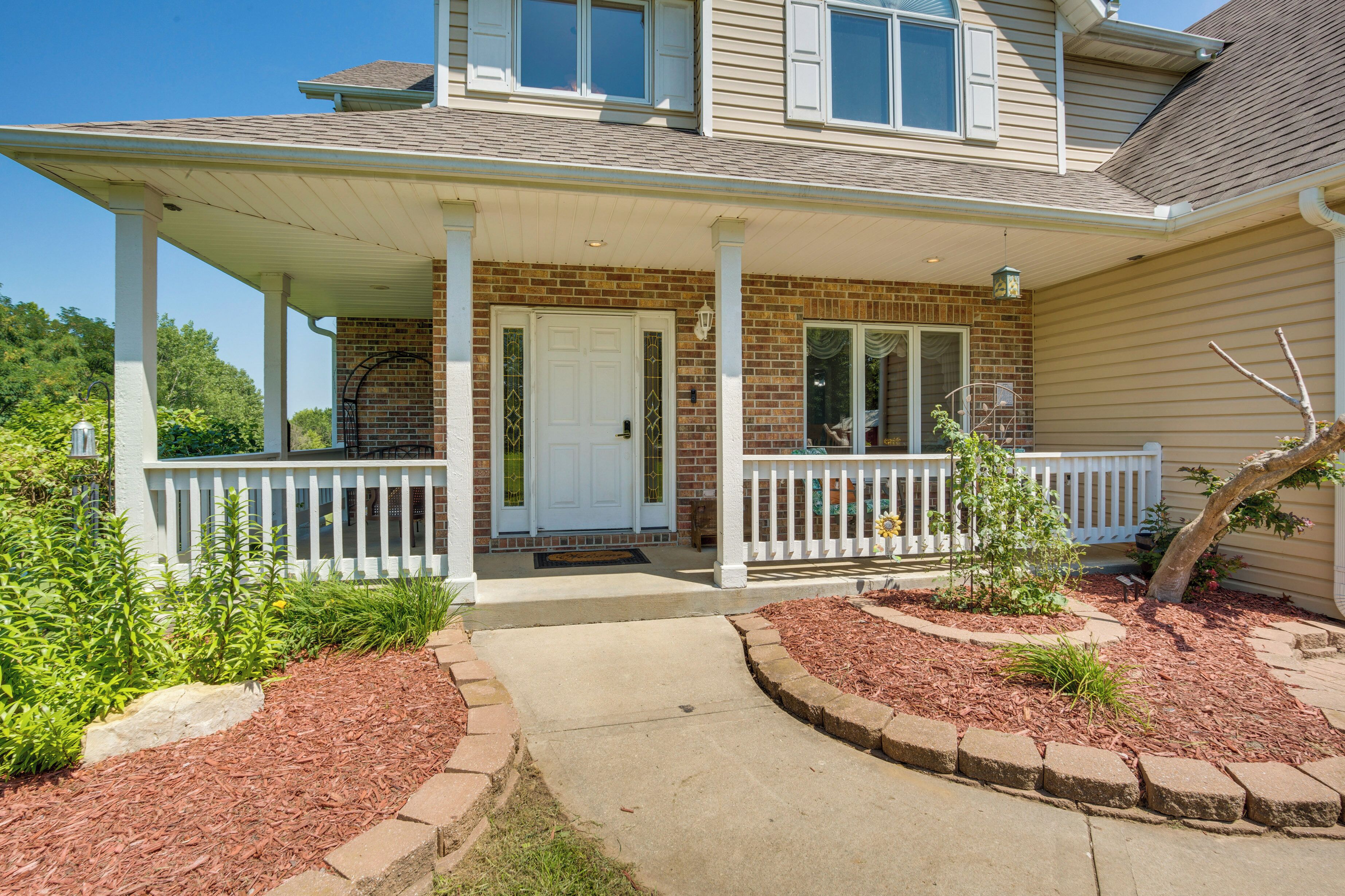 A two-story house with a covered porch, brick exterior, and a front door.