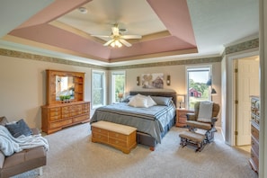 A bedroom with a large bed, a wooden dresser, a bench, a chair, and a ceiling fan. - Studio Suite & Country Views! Sibley Group Retreat (Sibley)