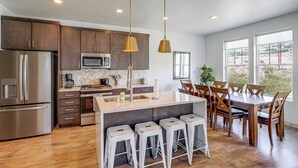 A modern kitchen with stainless steel appliances, a herringbone tile backsplash, and a central island with bar stools. - Hot Tub, Mtn & Lake Views! Group Abode in Daniel (Heber City)