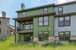 A two-story building with a green exterior, stone accents, and multiple windows. - Hot Tub, Mtn & Lake Views! Group Abode in Daniel (Heber City)