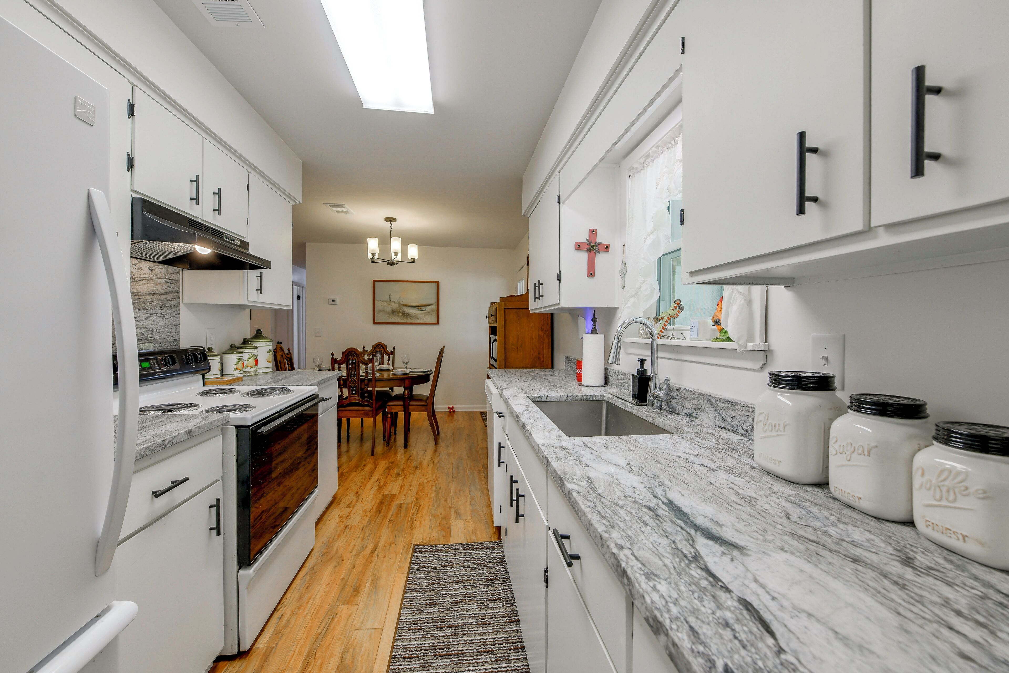 A modern kitchen with white cabinetry, a marble countertop, and a central island.