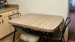 A dining table with four chairs, a coffee maker, and a decorative plate on the wall.