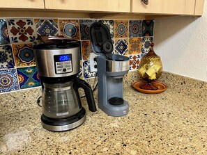Een koffiezetapparaat, een waterkoker en een decoratieve vaas op een keukenblad.