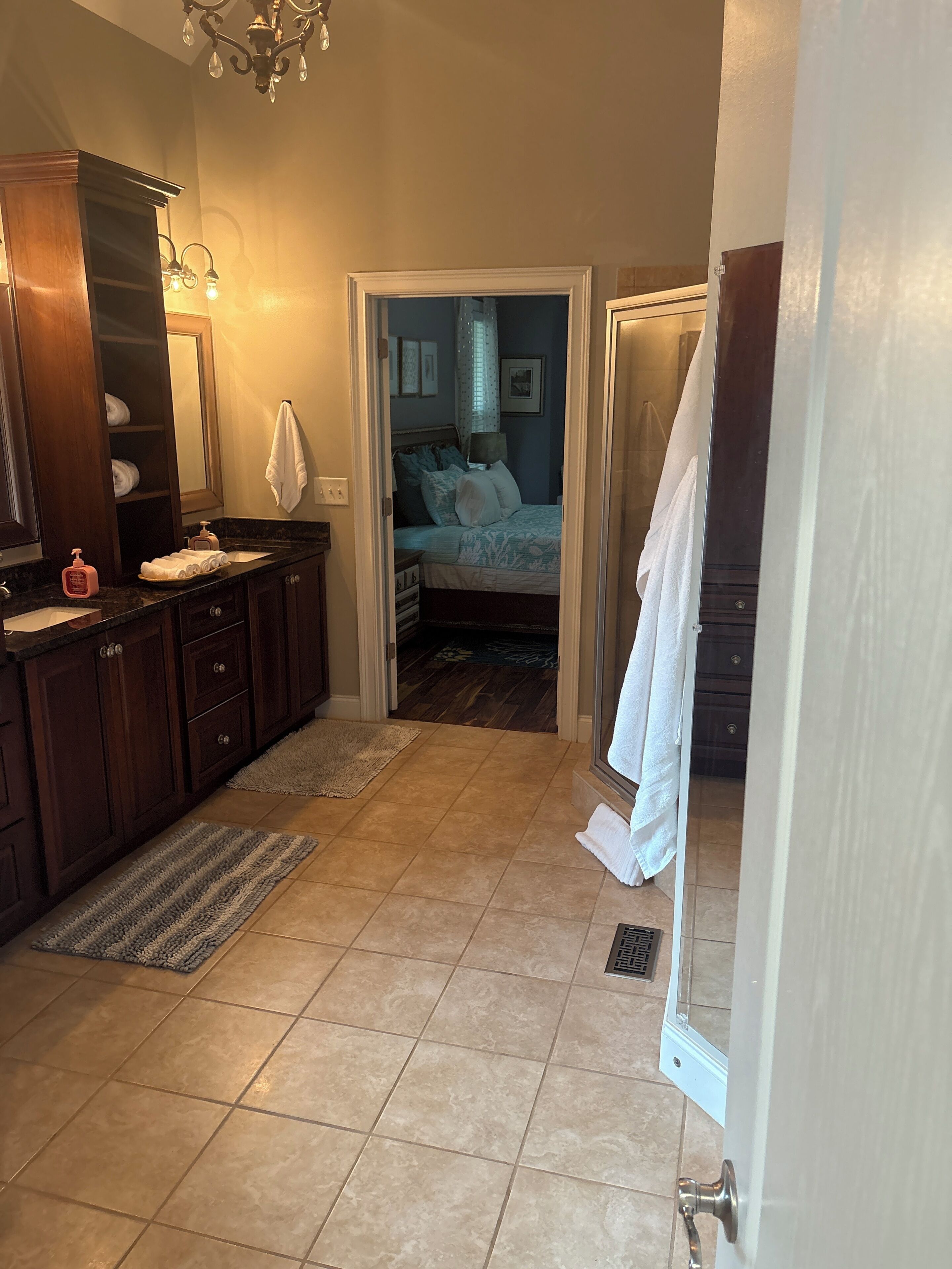A bathroom with a double sink, a mirror, a towel rack, and a shower area.