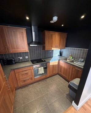 Una cocina compacta con gabinetes de madera, estufa a gas y salpicadero de azulejos.