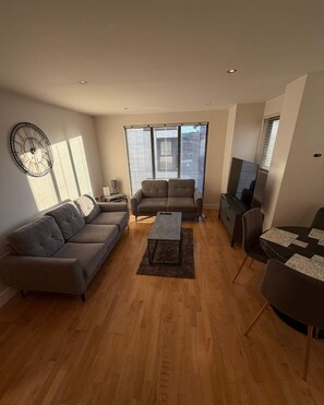 Una sala de estar con sofá, sillones, una mesa de centro y televisor.