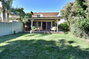 A residential backyard with a covered patio, a lawn, and a fence. - The Beach Garden at Fingal Bay (Fingal Bay)