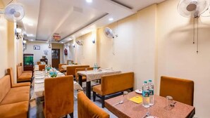 Ein Restaurant mit mehreren Tischen und Sitzecken, Deckenventilatoren und einem sichtbaren Wasserspender.