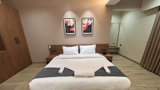Un dormitorio moderno con una cama grande, cabecera de madera, mesitas de noche y obras de arte en las paredes.