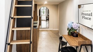 A loft-style room with a wooden staircase, a dining area with a table and chairs, and a view into the kitchen.