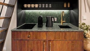 Una cocina con un microondas negro, una cafetera y un lavabo.