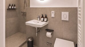 Un baño moderno con ducha, lavamanos, inodoro y un espejo con luz.