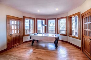 A room with a pool table, large windows, wooden doors, and a ceiling with recessed lighting. - Two Bears | Mountain Views and Game Nights (Franklin)