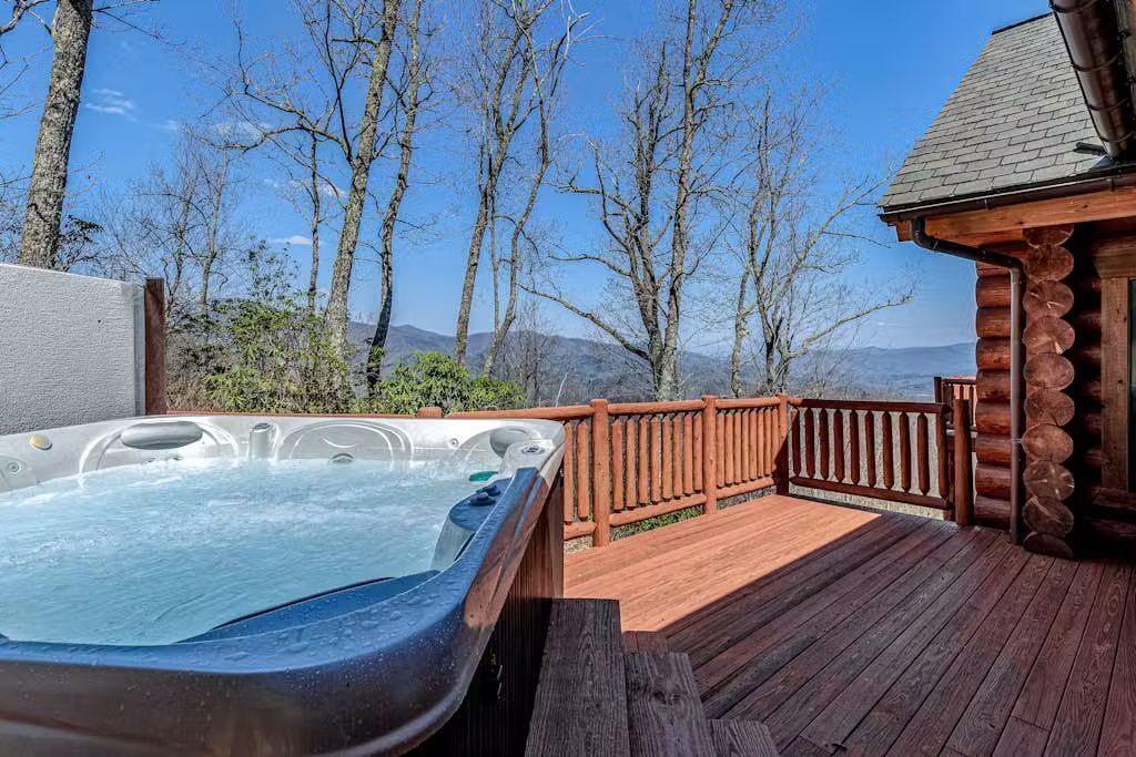 A hot tub on a wooden deck with a view of trees and mountains.