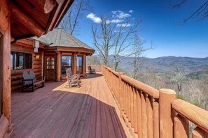 A wooden cabin with a deck, a covered seating area, and a view of the mountains. - Two Bears | Mountain Views and Game Nights (Franklin)