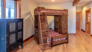 Ein Stockbett mit einer Leiter, ein Schrank mit Verzierungen und eine Holztür.